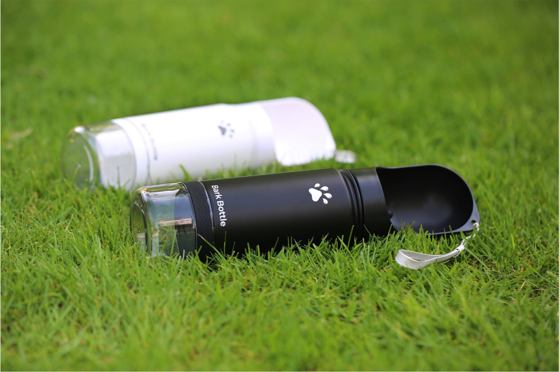Black and white pet water bottles on grass